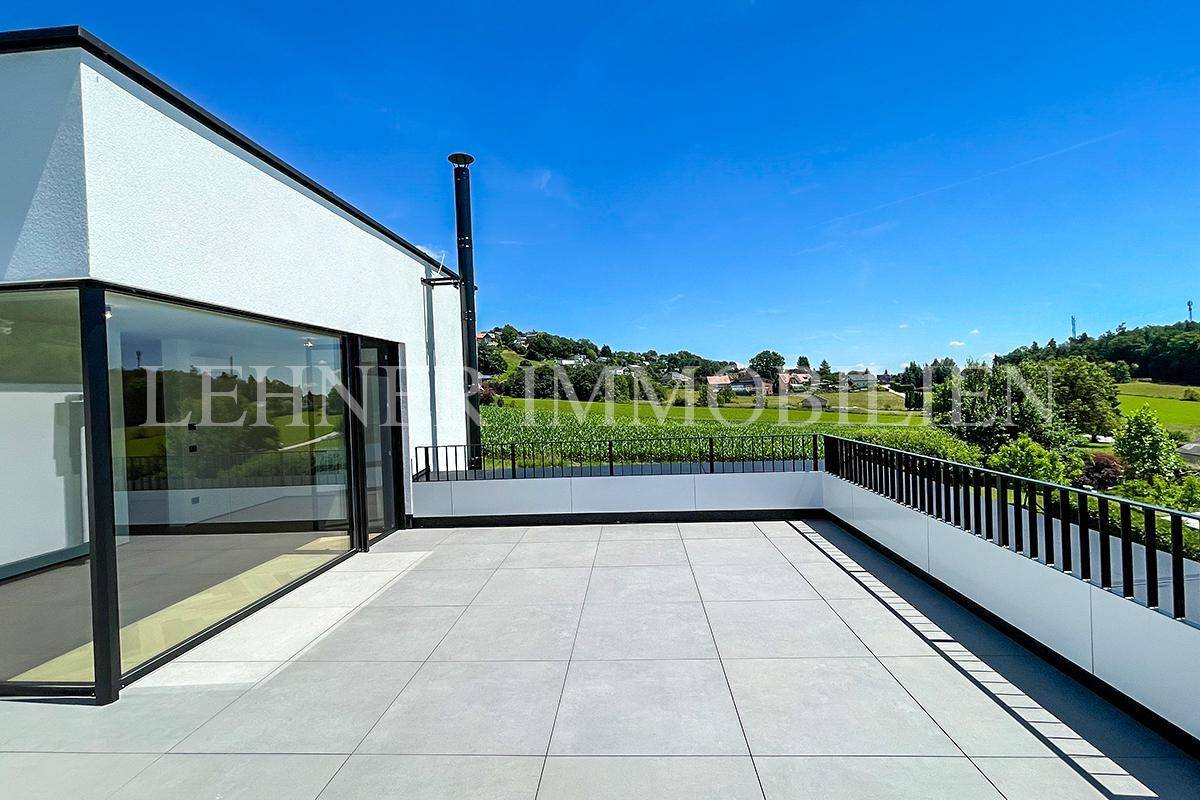 Große Dachterrasse mit Fliesenboden und weitem Blick auf Felder und Hügel.