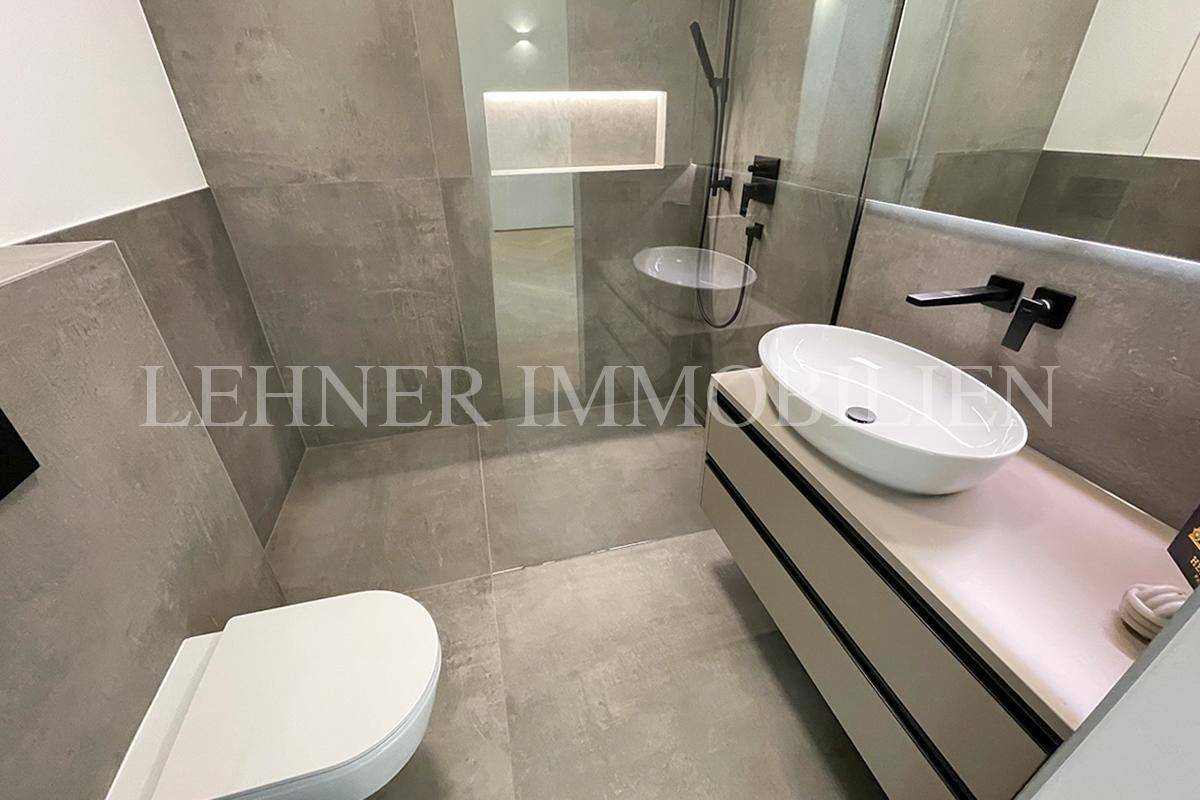 Modernes Badezimmer mit begehbarer Dusche, Aufsatzwaschbecken und grauen Fliesen.