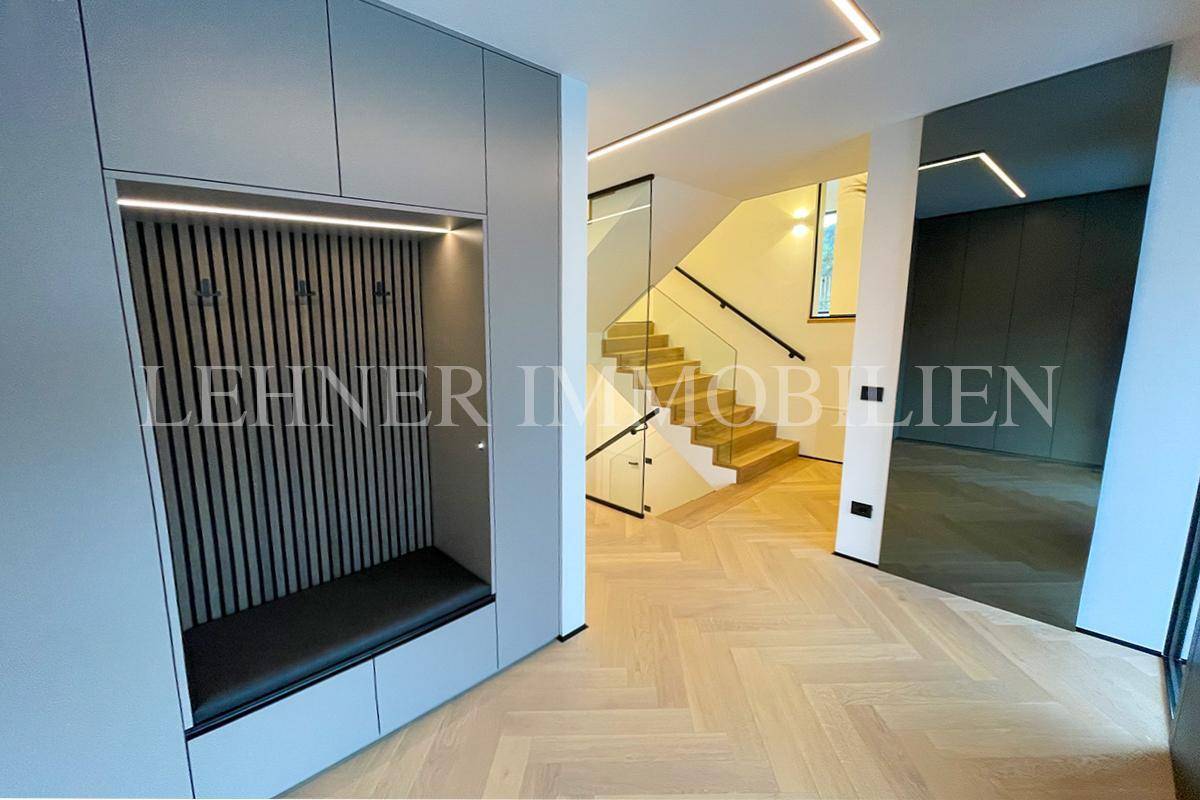 Heller Flur mit moderner Treppe aus Holz und Glasgeländer.