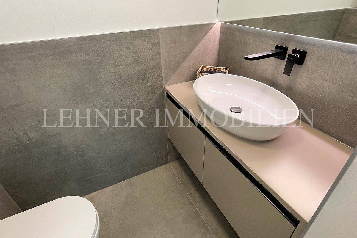 Modernes Gäste-WC mit Wand-WC, Aufsatzwaschbecken und grauen Fliesen.