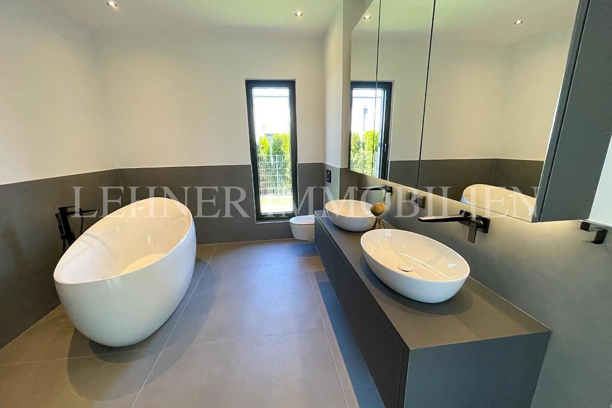 Geräumiges Badezimmer mit freistehender Badewanne, WC und Doppelwaschbecken.