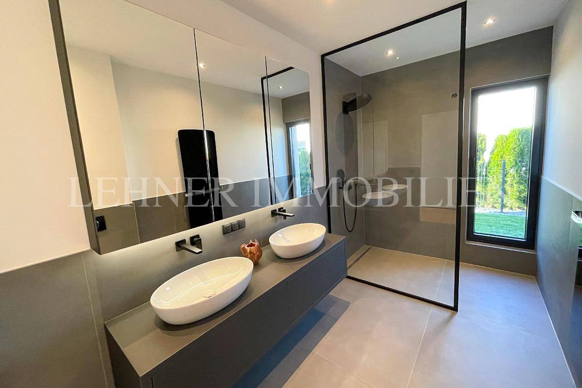 Großes Badezimmer mit Doppelwaschbecken, begehbarer Dusche und Fenster.