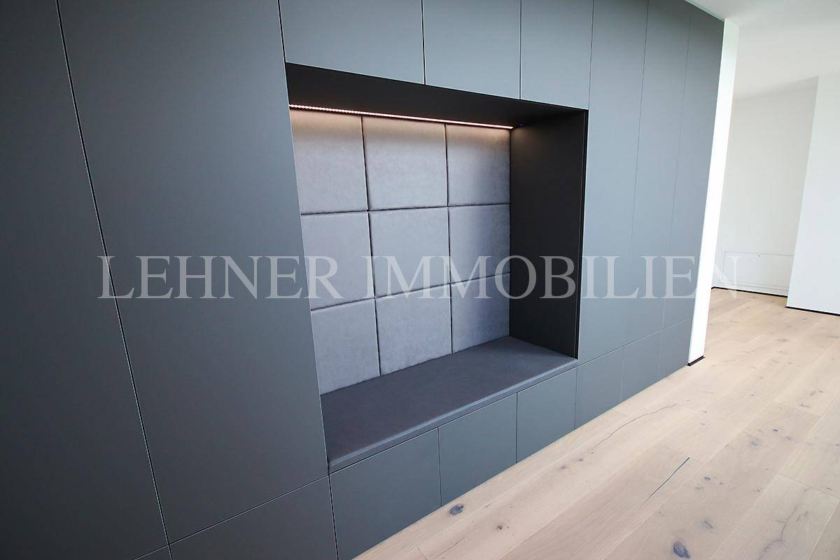 Moderner Einbauschrank mit Sitzgelegenheit und indirekter Beleuchtung im Flurbereich.
