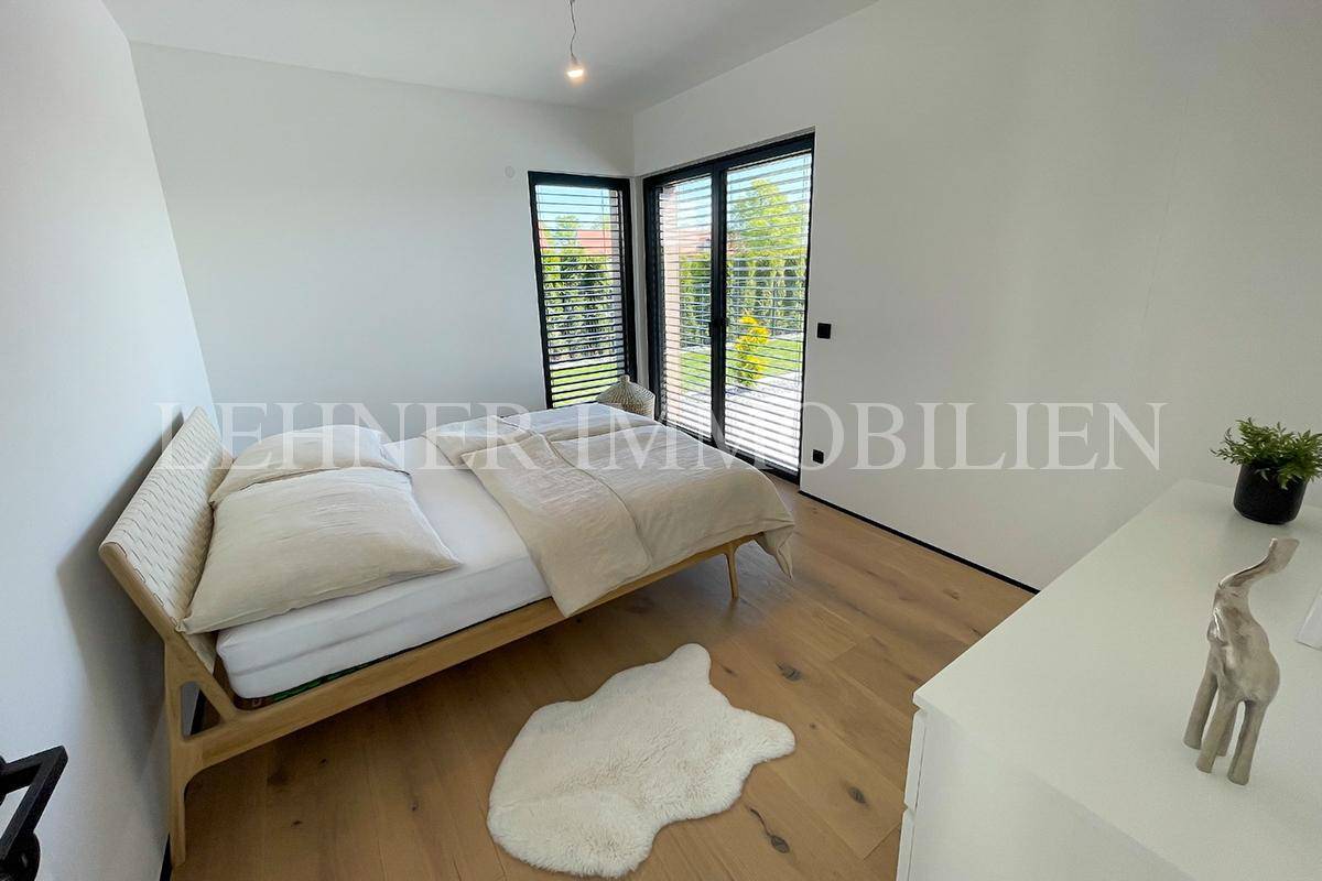 Helles Schlafzimmer mit Holzboden und Zugang zum Außenbereich durch große Schiebetüren.