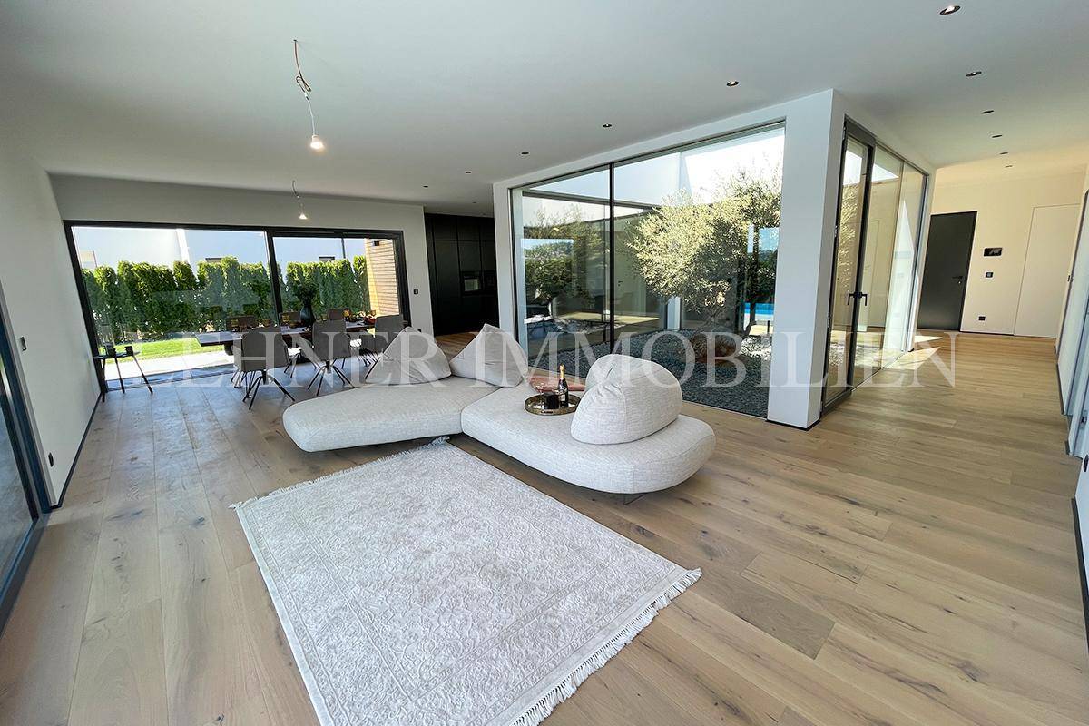 Heller Wohn-Essbereich mit modernem Design und Blick auf den Innenhof und den Poolbereich.