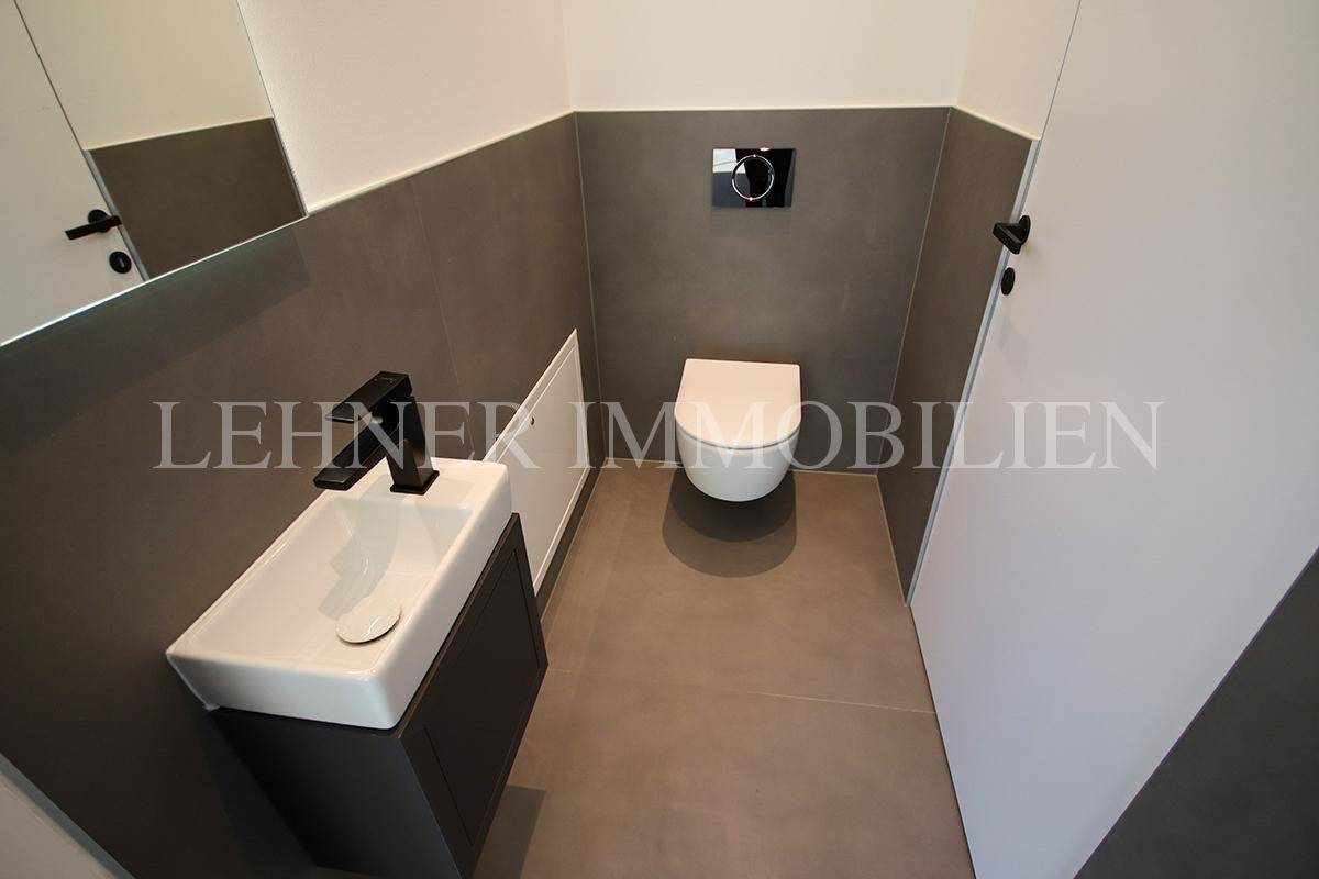 Modernes Gäste-WC mit wandhängender Toilette und kleinem Waschbecken.