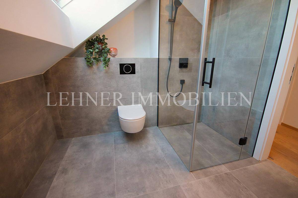 Modernes Badezimmer im Dachgeschoss mit begehbarer Dusche, Wand-WC und Fliesenboden.