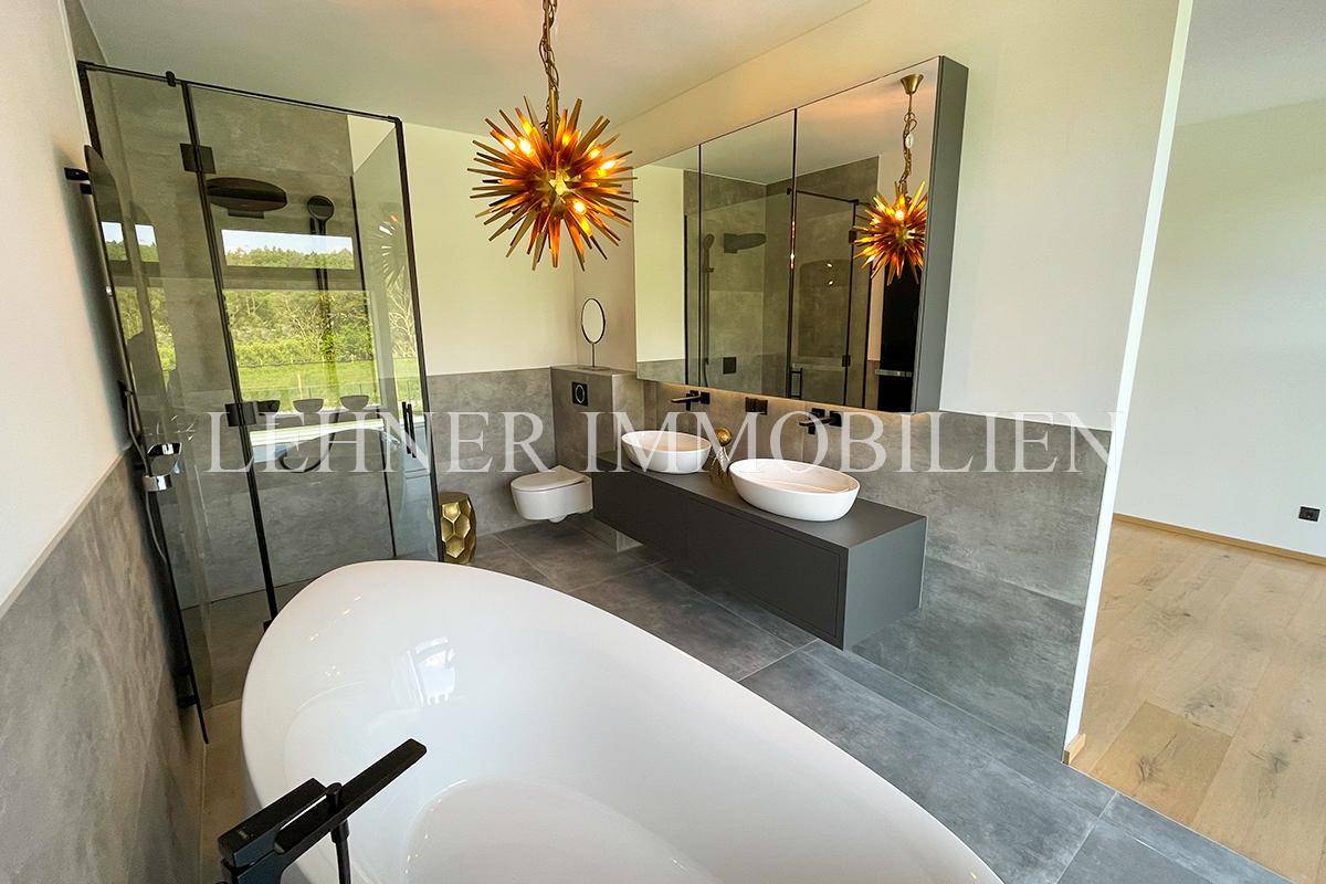 Elegantes Badezimmer mit freistehender Wanne, begehbarer Dusche und modernen Armaturen.