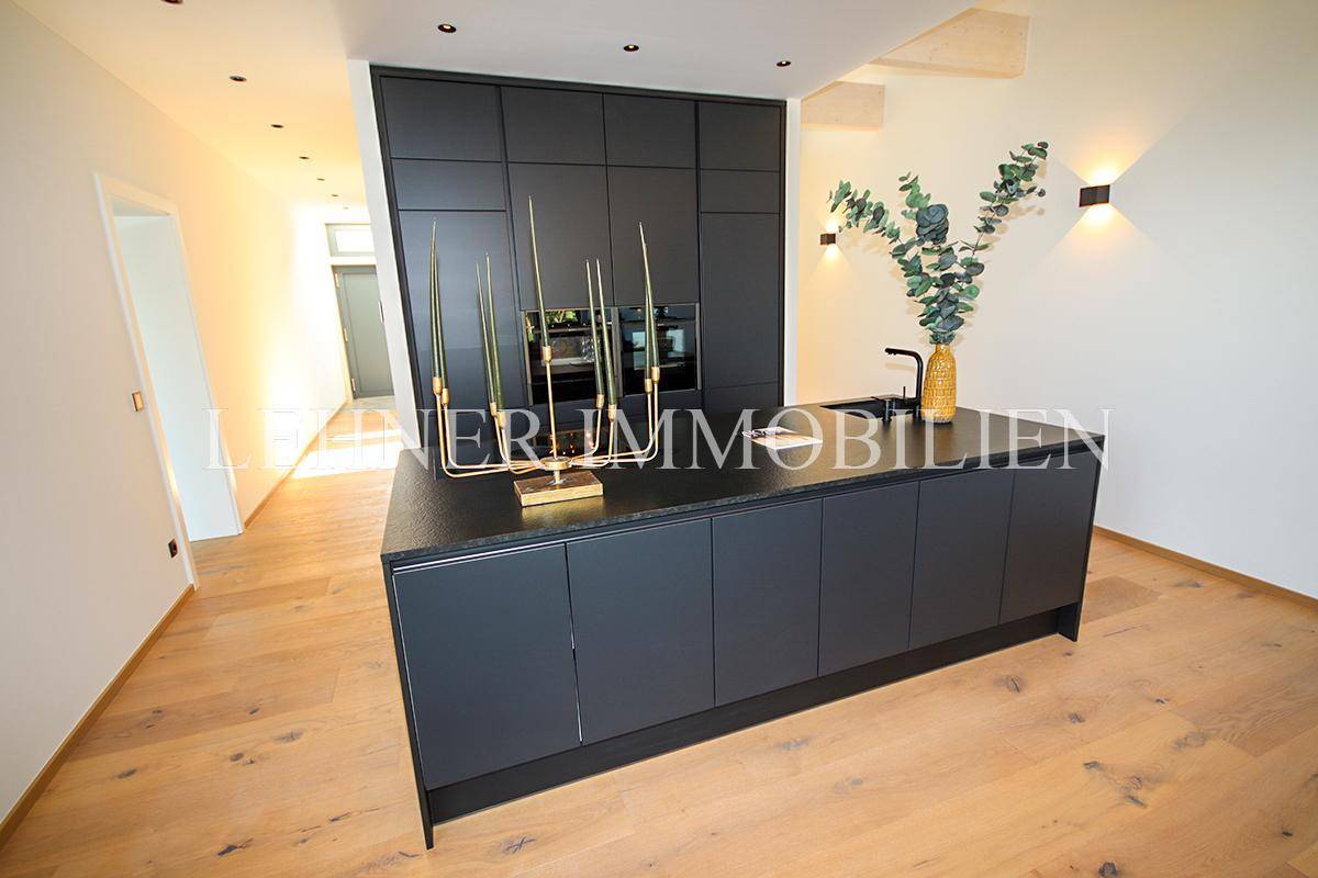 Stilvolle schwarze Einbauküche mit Kücheninsel und integrierten Geräten, modern gestaltet.