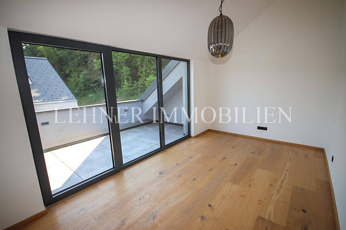 Heller Raum mit Holzboden und Zugang zu einer privaten Dachterrasse mit Ausblick.
