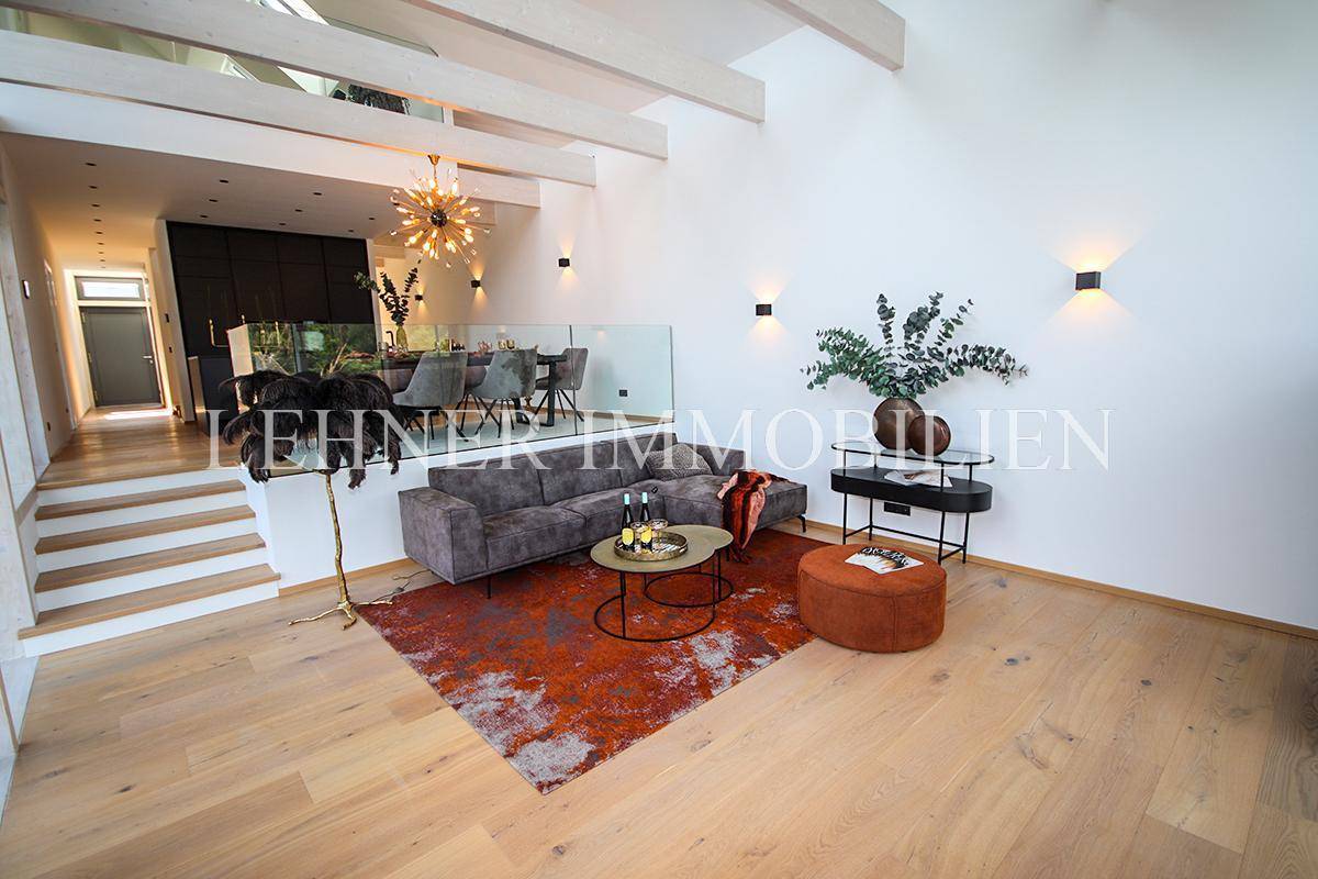 Geräumiges Wohnzimmer mit hohen Decken, Holzboden und offener Gestaltung zum Essbereich.
