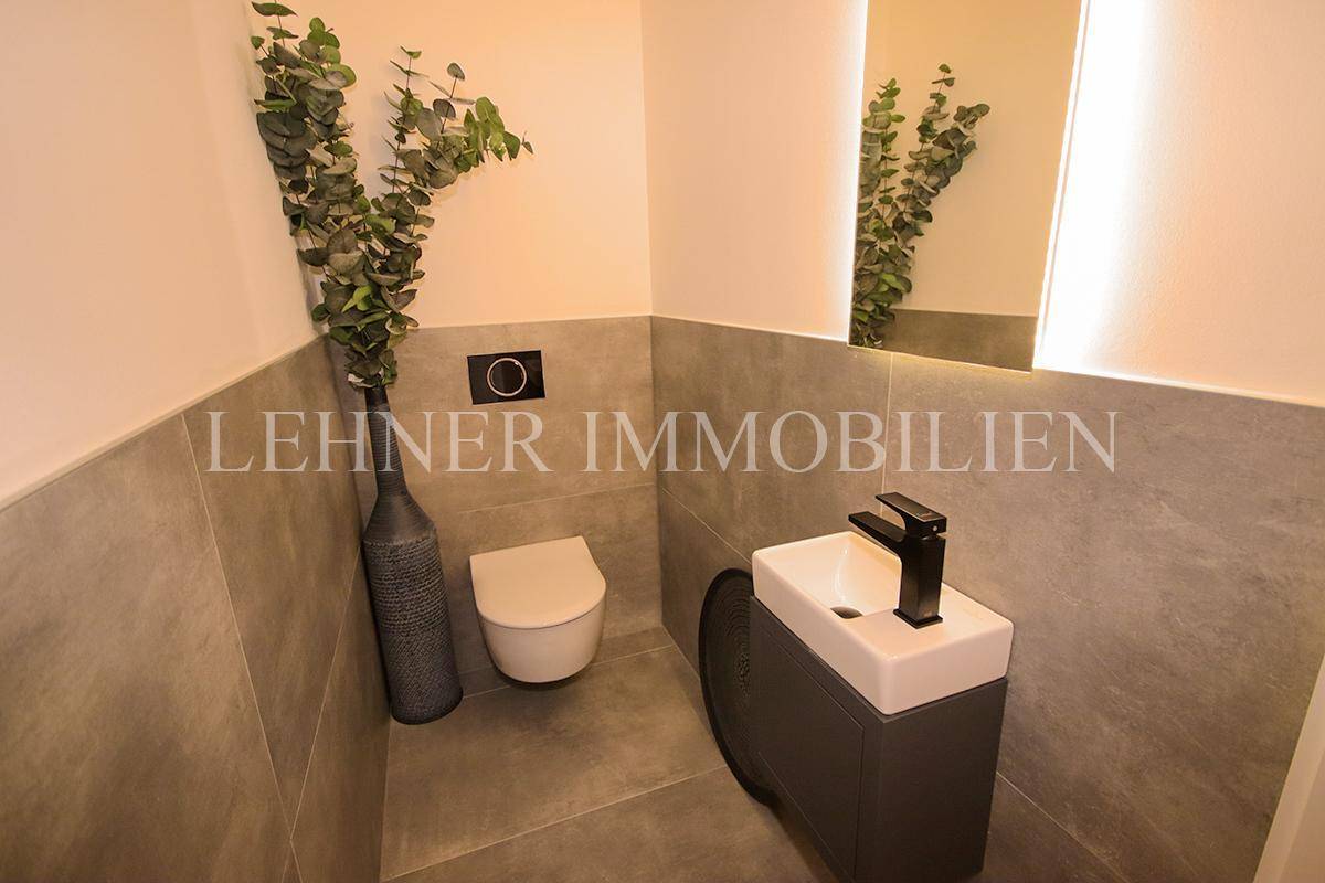 Stilvolles Gäste-WC mit Wand-WC, kleinem Waschbecken und modernen Fliesen.