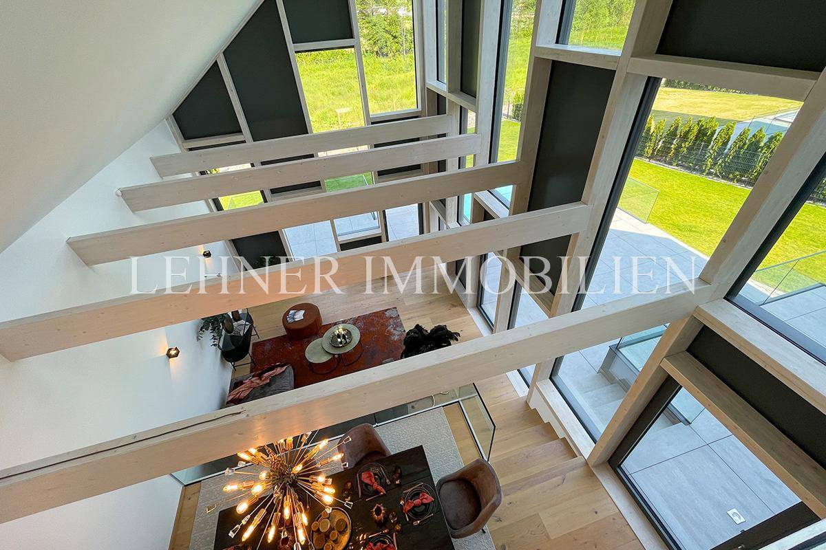 Panoramaansicht von der oberen Etage auf den offenen Wohn- und Essbereich mit hohen Decken.