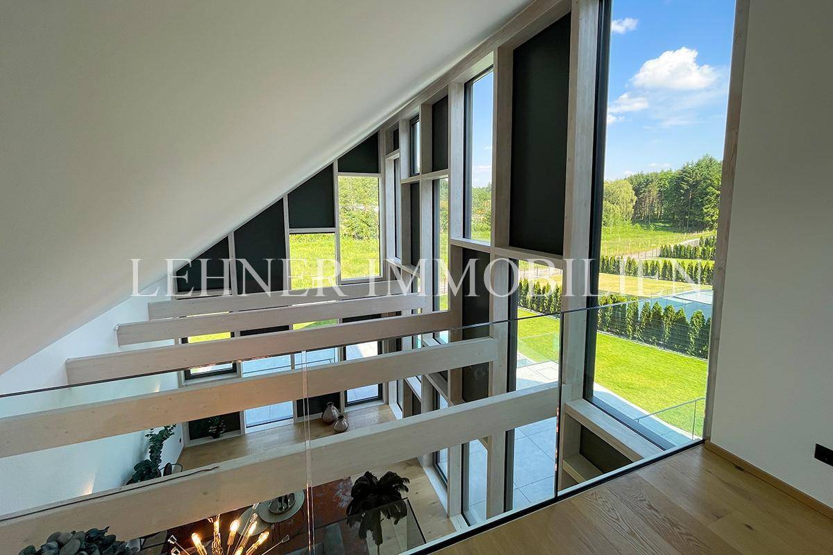 Blick von der Galerie im Dachgeschoss auf den offenen Wohnbereich mit großen Fenstern.