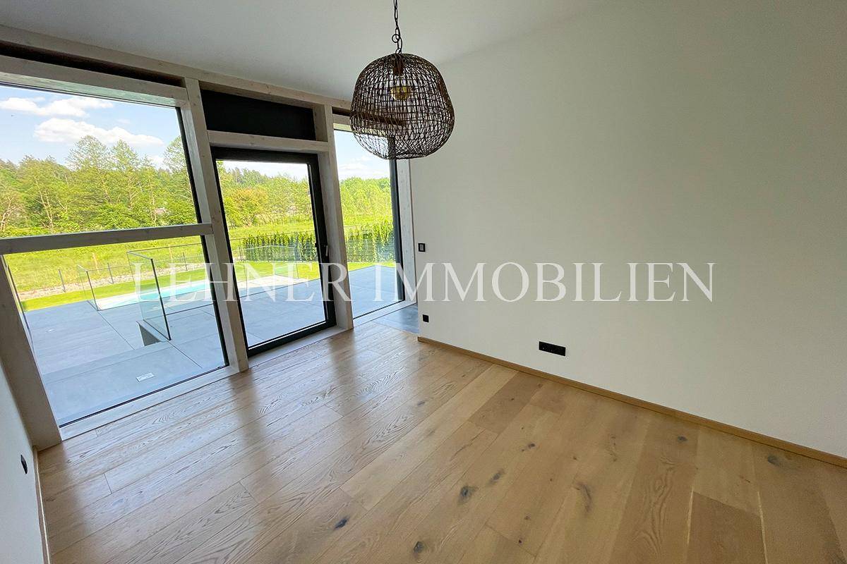 Heller Raum mit großen Fenstern und Holzboden, bietet Zugang zum Außenbereich.