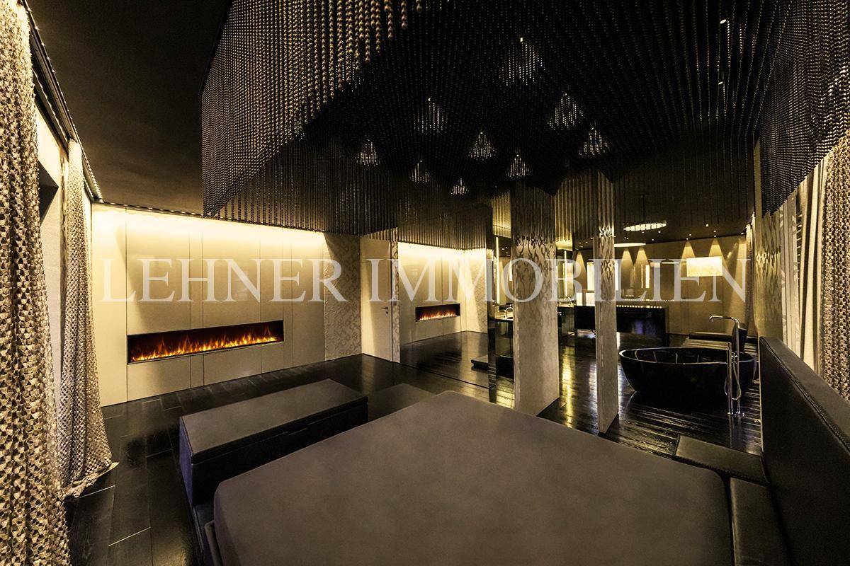 Luxuriöses Schlafzimmer mit integriertem Kamin, dunklem Ambiente und dekorativer Decke.