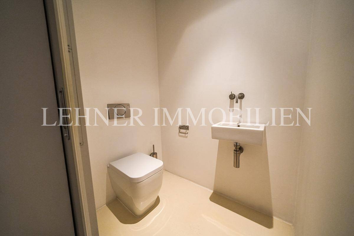 Modernes Gäste-WC mit Wand-WC, kleinem Waschbecken und minimalistischem Design.