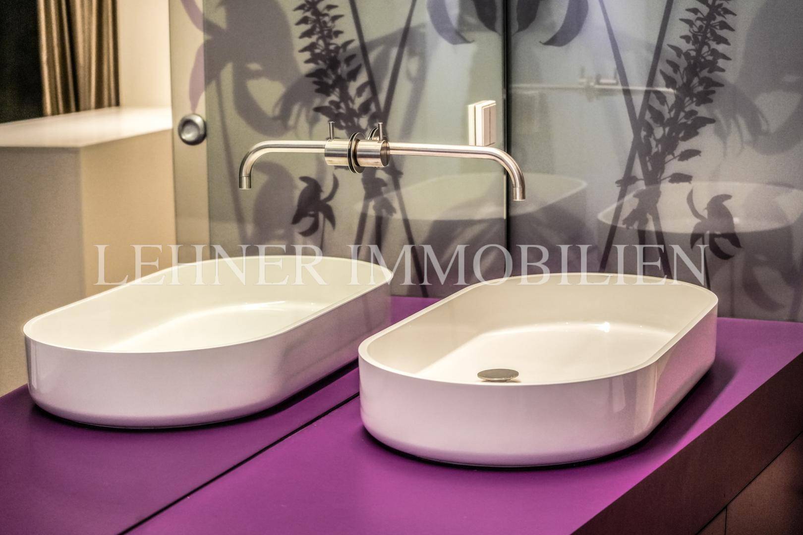 Detailansicht der modernen Doppelwaschbecken mit eleganten Armaturen in lila Umgebung.