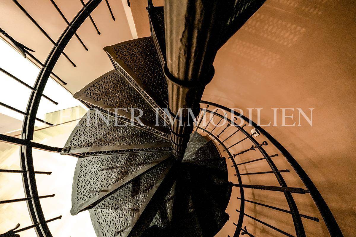 Detailaufnahme der kunstvollen gusseisernen Wendeltreppe mit filigranen Mustern.