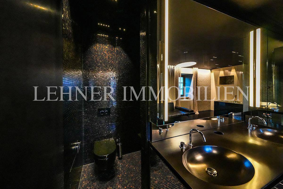 Modernes Badezimmer mit Wand-WC, Doppelwaschbecken und dunklen Mosaikfliesen.