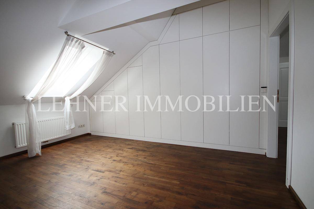 Dachbodenraum mit Holzboden und maßgefertigten weißen Einbauschränken unter der Dachschräge.