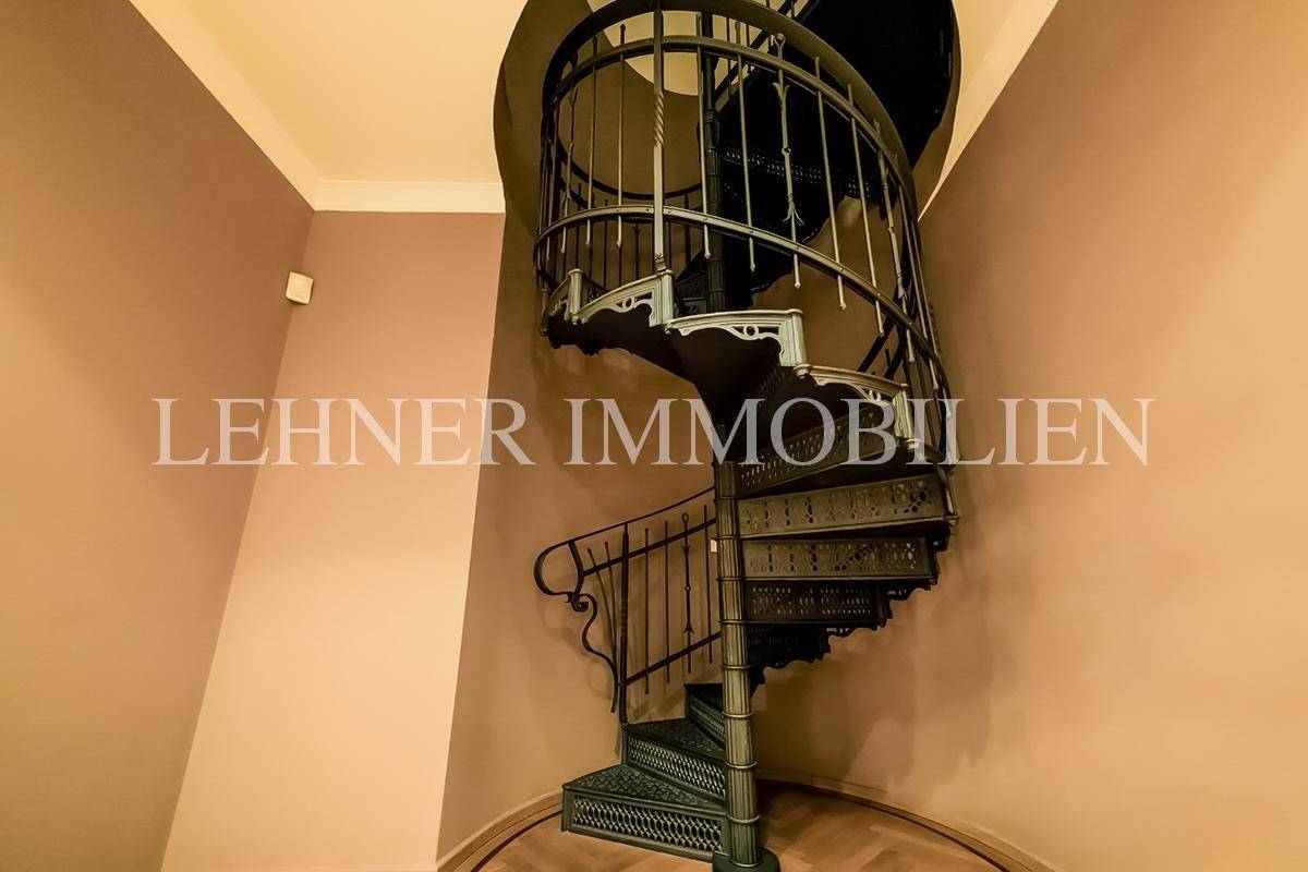 Elegante Wendeltreppe aus Metall in einem hellen Flur mit Parkettboden.