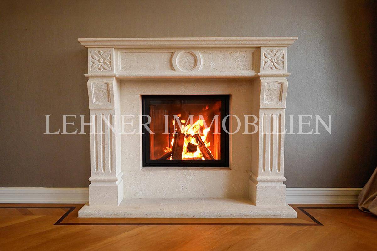 Detailansicht des eleganten Kamins mit geschnitzten Verzierungen und brennendem Feuer.