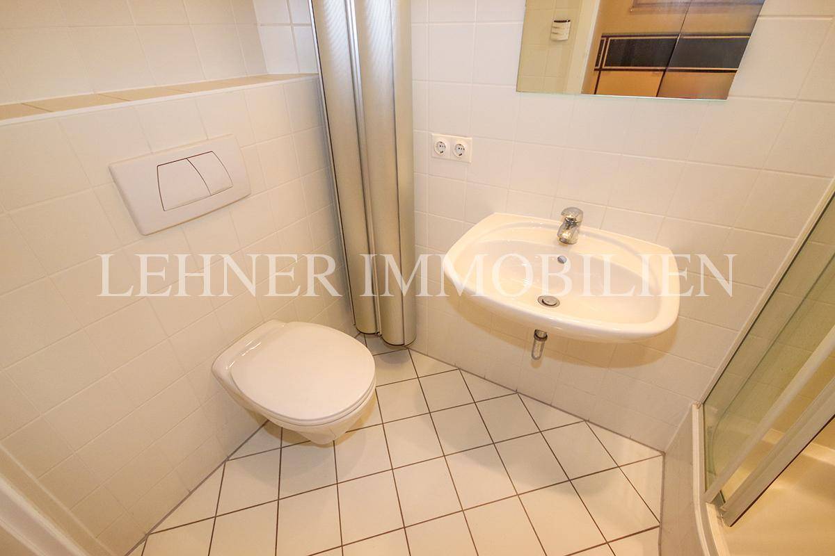 Funktionales Badezimmer mit Duschkabine, Waschbecken und Wand-WC.