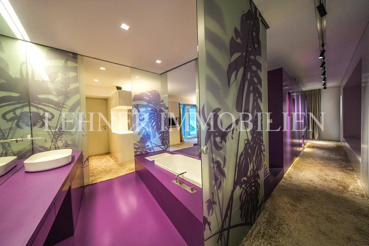 Modernes Schlafzimmer mit integriertem Badezimmer, lila Akzenten und dekorativen Wänden.