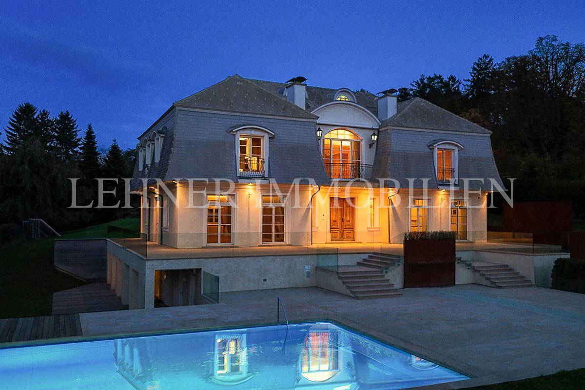 Beleuchtete Villa bei Nacht mit glitzerndem Pool und stimmungsvoller Außenbeleuchtung.