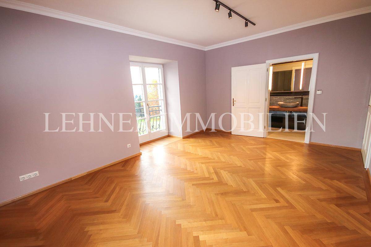 Helles Schlafzimmer mit Fischgrätparkett, lila Wänden und Zugang zum französischen Balkon.