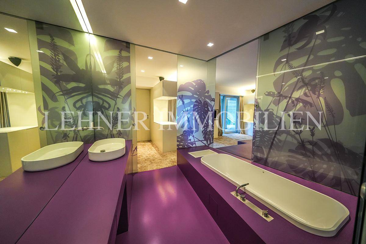Luxuriöses Badezimmer mit lila Boden, Doppelwaschbecken und integrierter Badewanne.