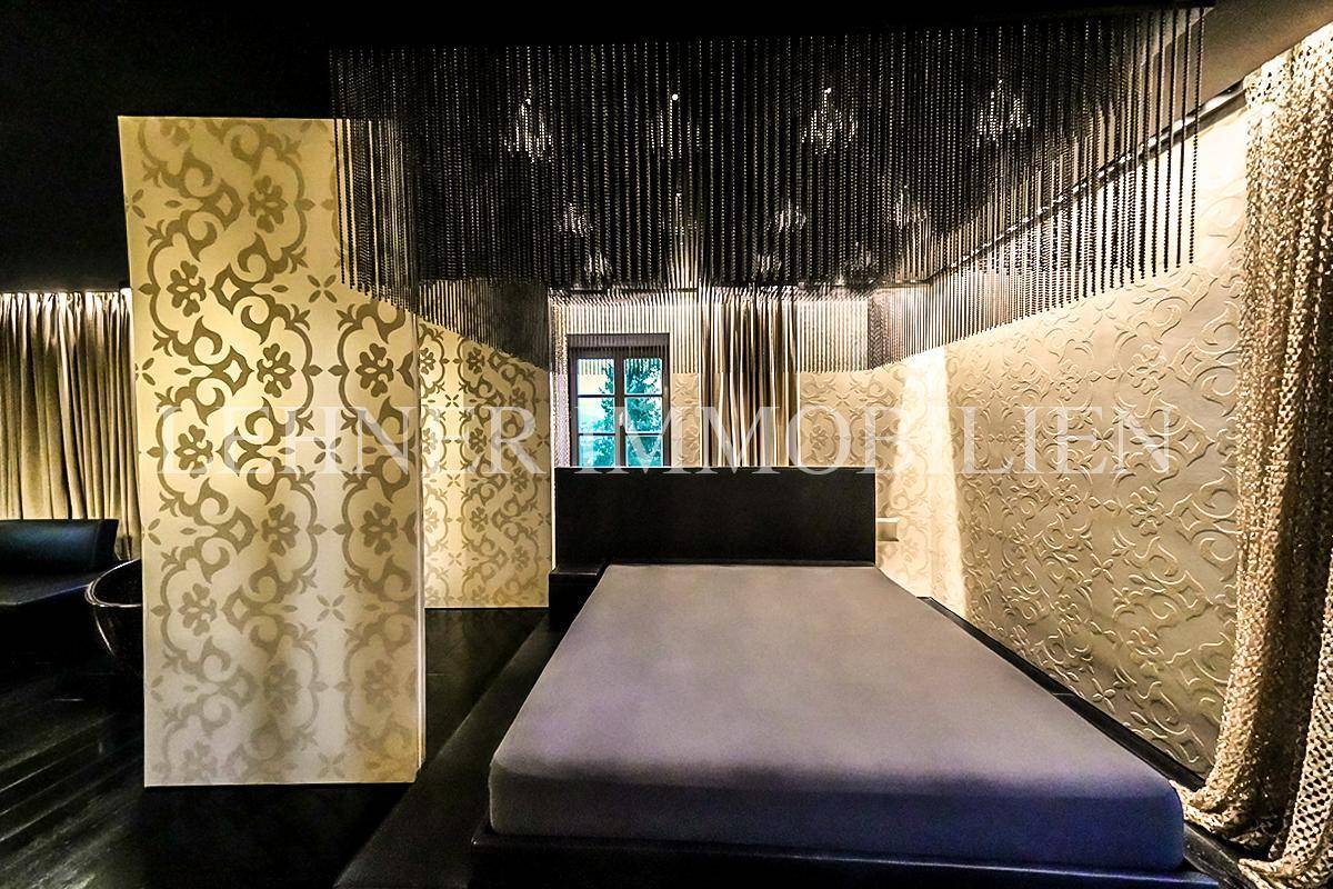 Stilvolles Schlafzimmer mit großem Bett, gemusterter Wand und dunklem Holzboden.