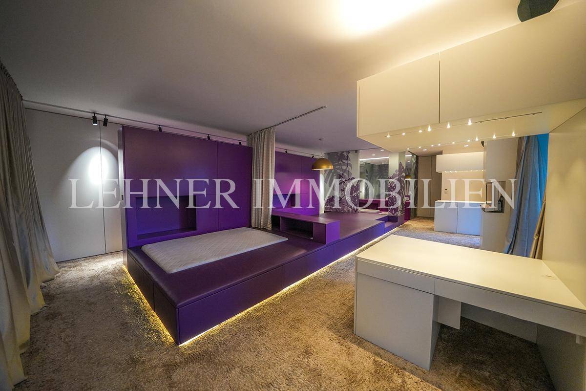 Modernes Schlafzimmer mit lila Podestbett, Teppichboden und integriertem Schreibtisch.
