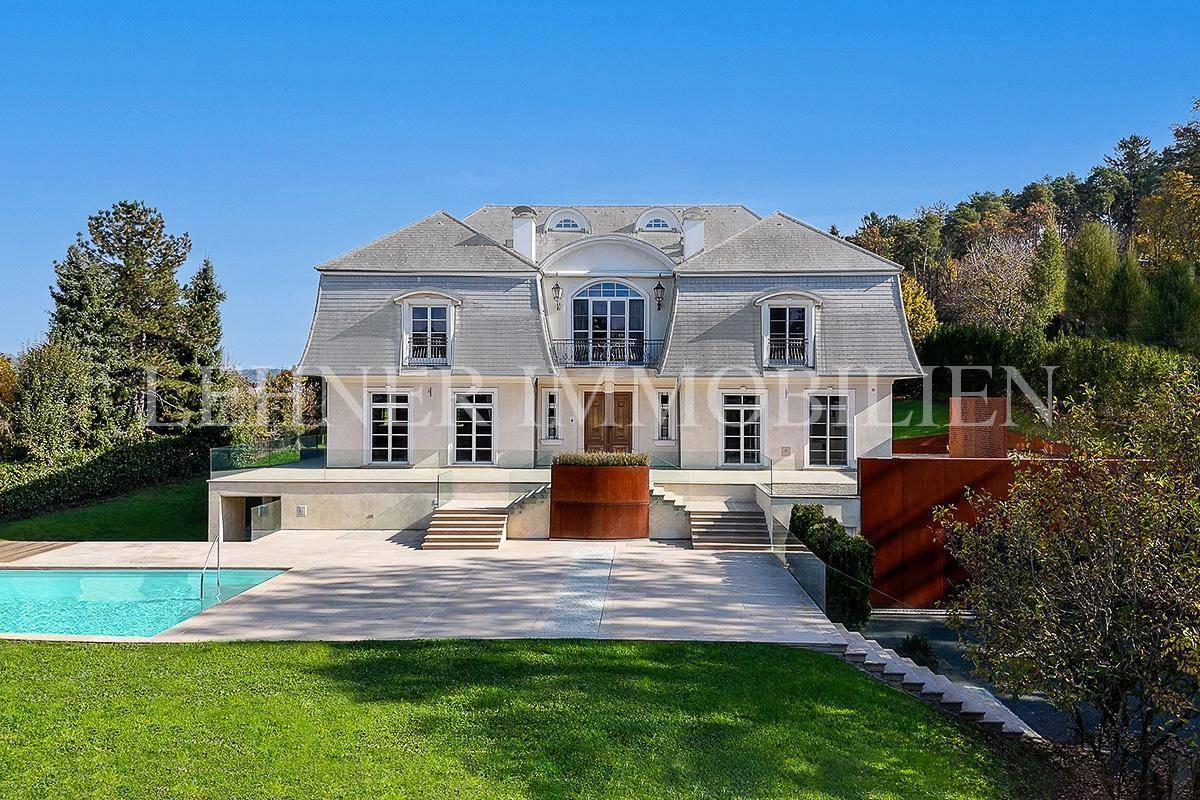 Prächtige Villa mit klassischer Architektur, großem Poolbereich und gepflegtem Rasen.