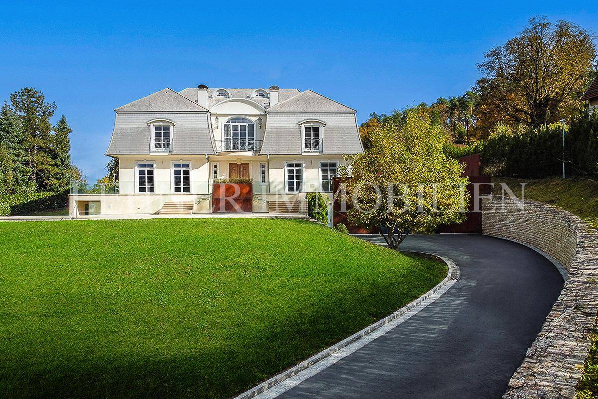Repräsentative Villa mit geschwungener Auffahrt und weitläufigem, grünem Vorgarten.