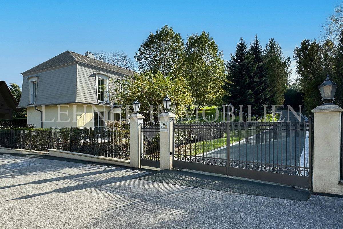 Elegantes Eingangstor mit schmiedeeisernen Details und Laternen, das zur Villa führt.
