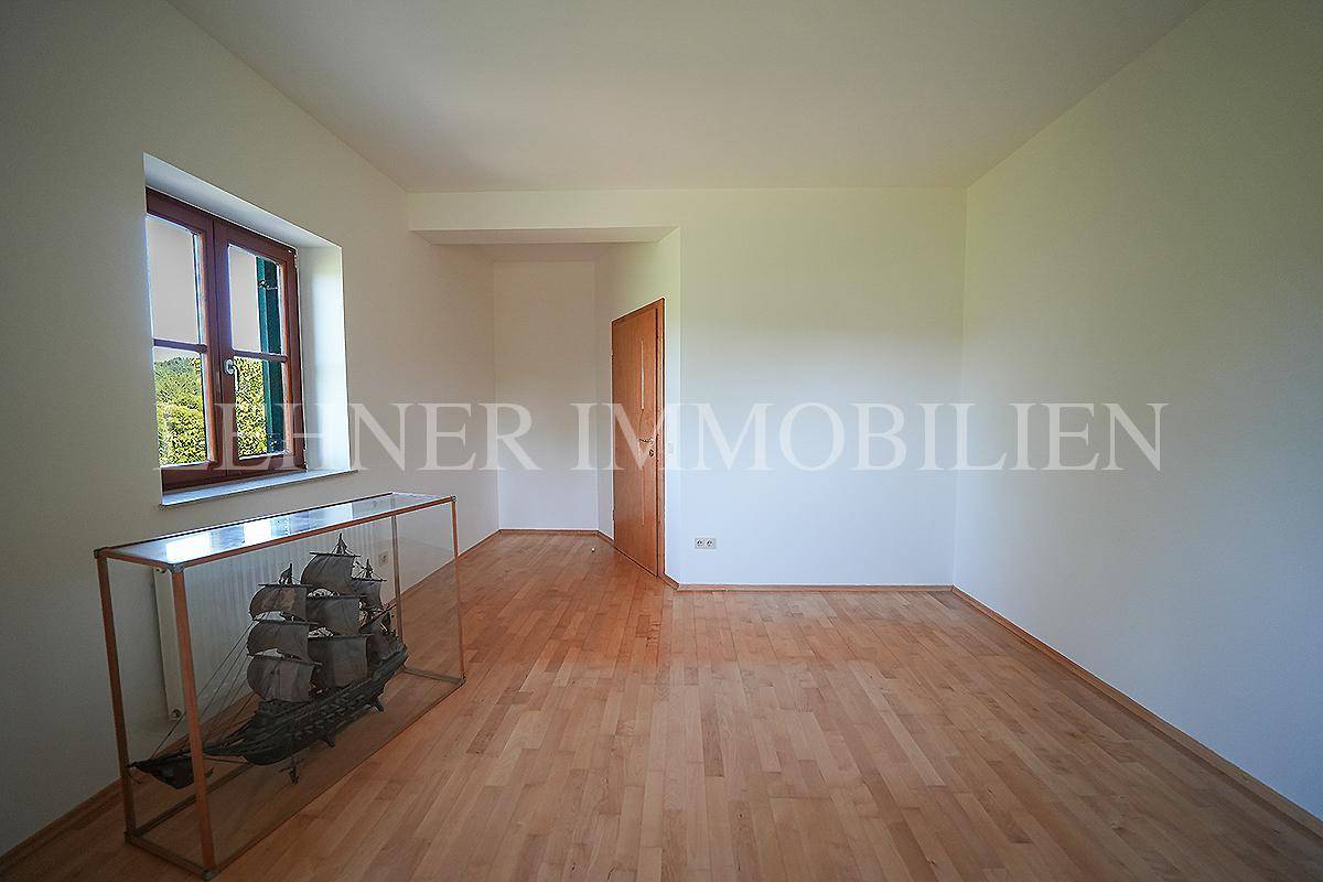 Geräumiges Zimmer mit Holzboden und Blick auf die grüne Umgebung.