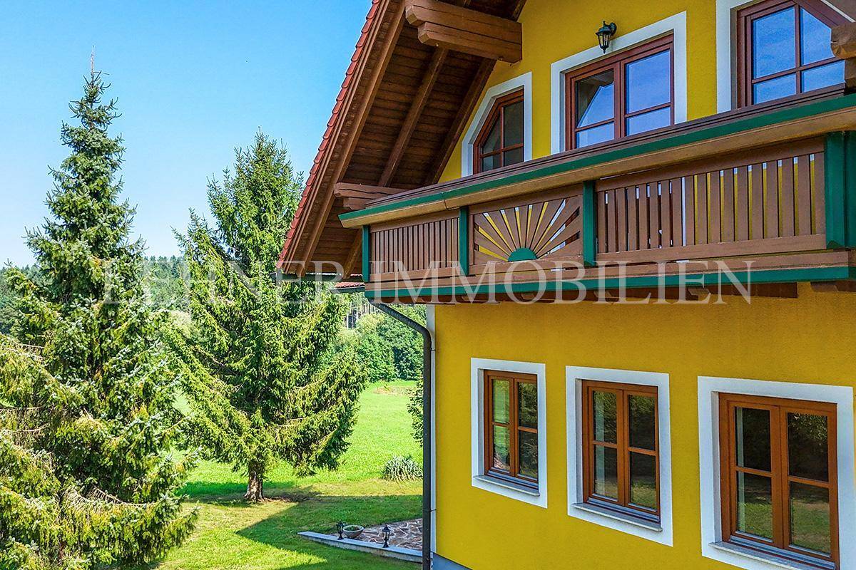 Holzbalkon mit traditionellem Geländer und weitem Blick über die grüne Landschaft.