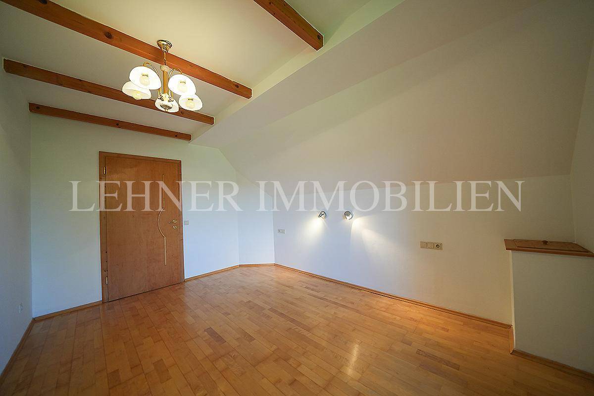 Helles Schlafzimmer im Dachgeschoss mit Holzbalken und Holzboden.