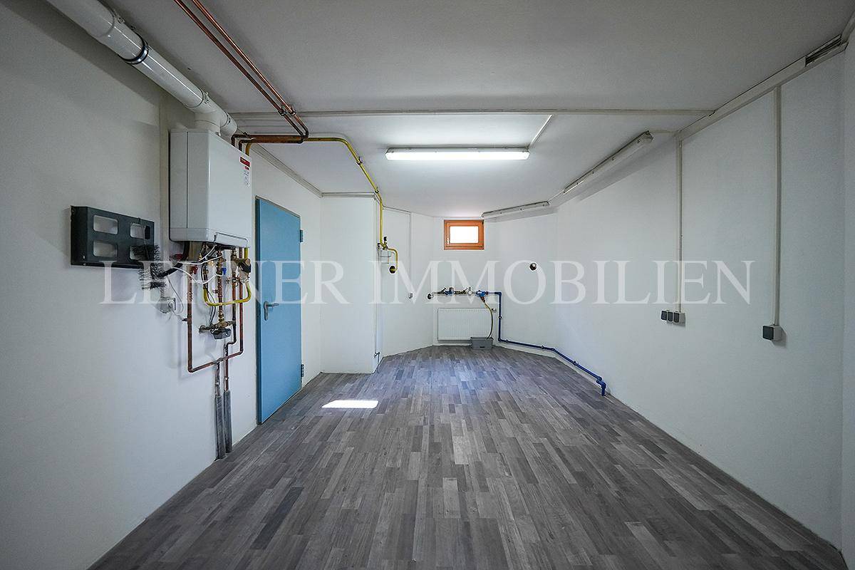 Heizraum im Keller mit Heizungsanlage, Leitungen und Laminatboden.