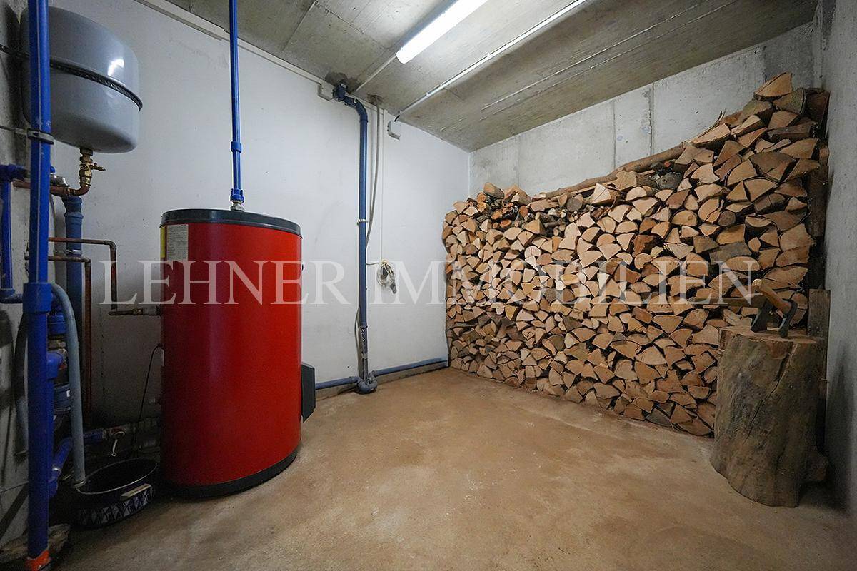 Kellerraum mit Holzstapel und Warmwasserspeicher.