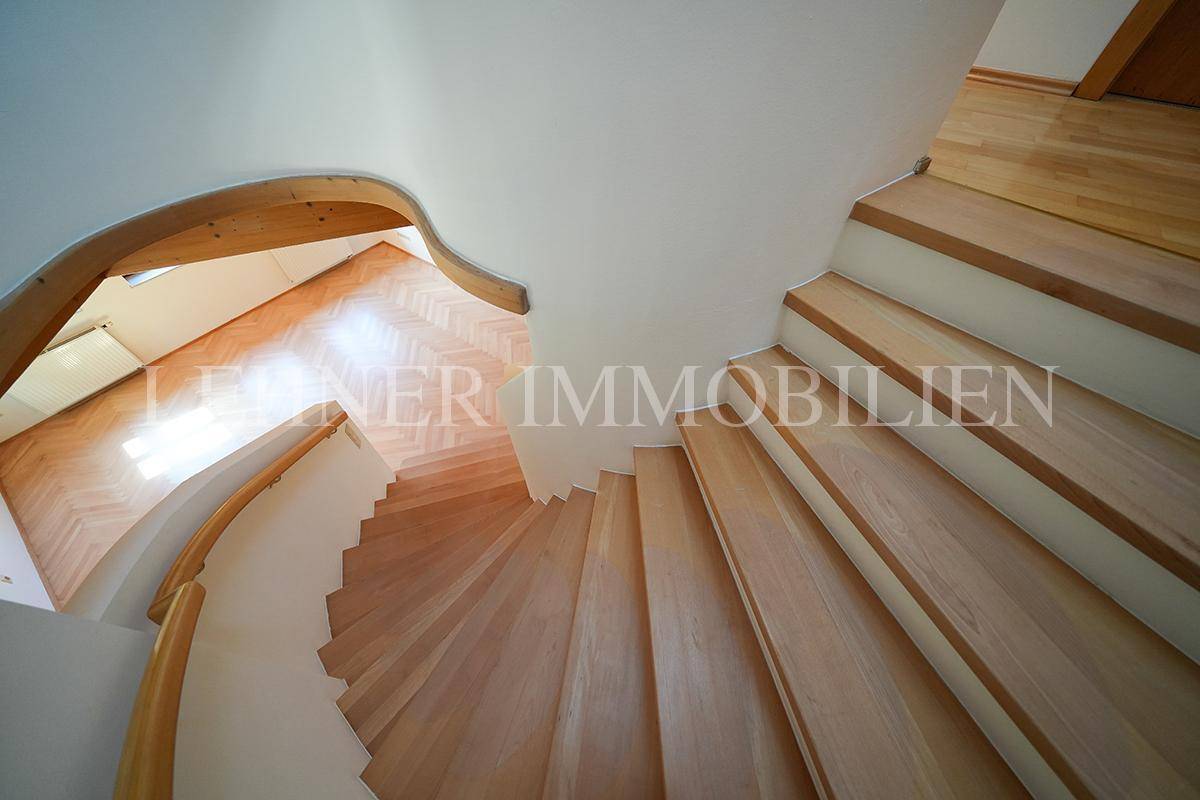 Elegante Wendeltreppe aus Holz mit geschwungenem Geländer, die nach oben führt.