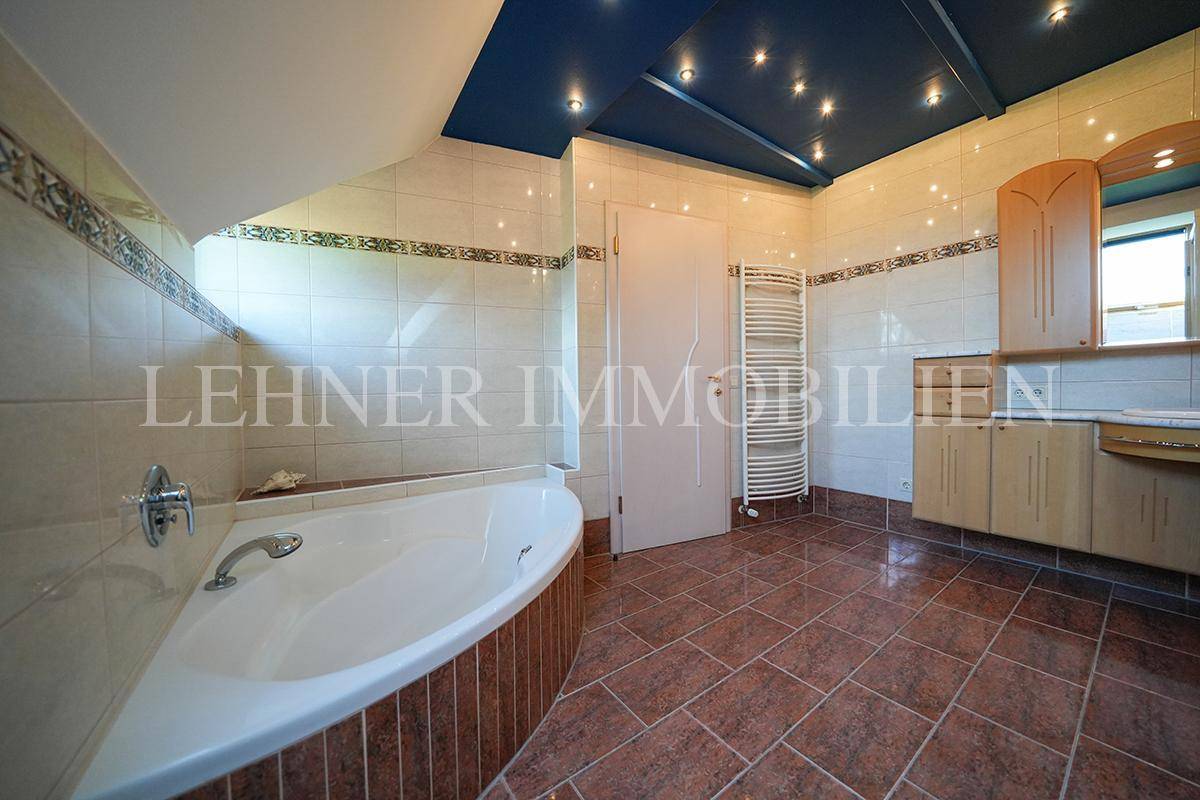 Geräumiges Badezimmer mit Badewanne, Dusche, beheiztem Handtuchhalter und blauer Decke.