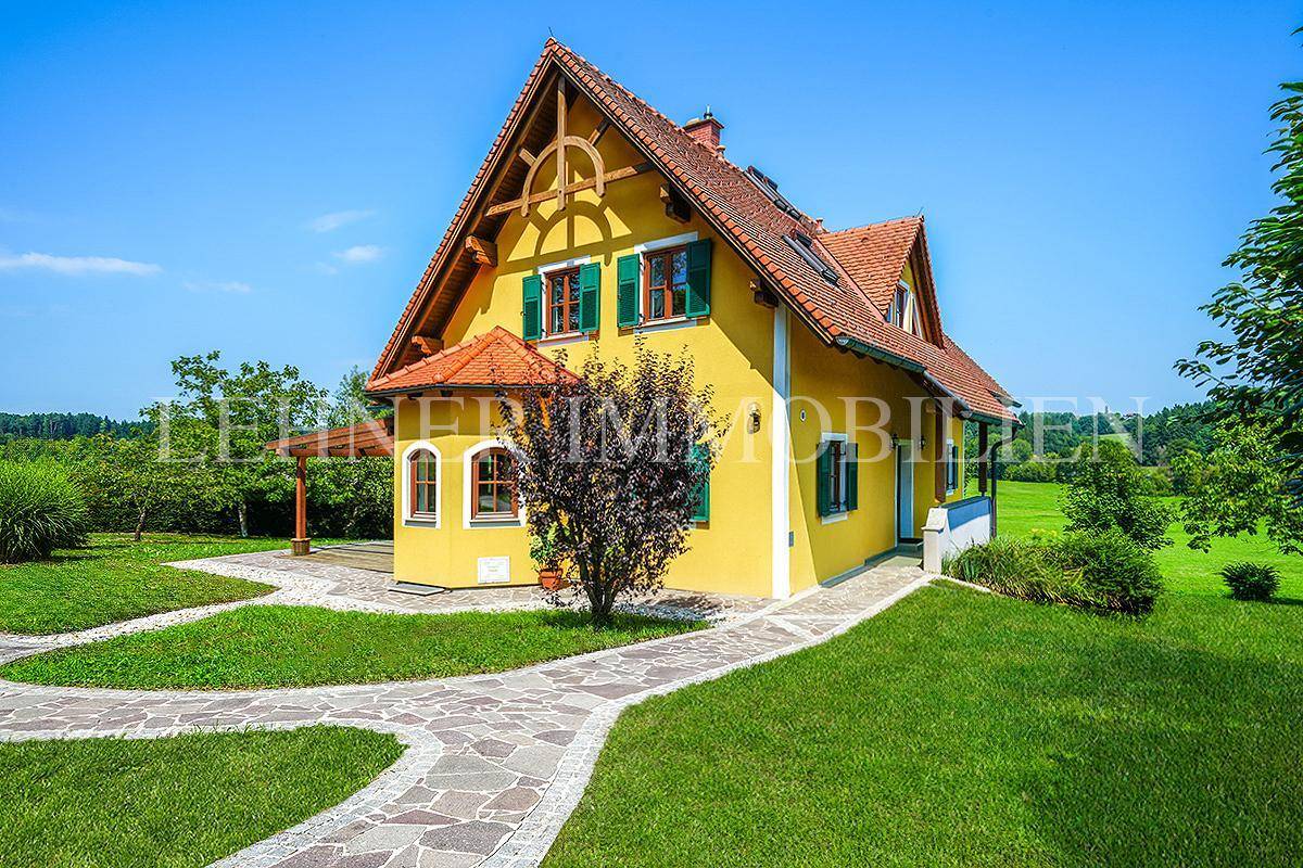 Malerisches Landhaus mit gelber Fassade und weitläufigem Garten, umgeben von idyllischer Naturlandschaft.