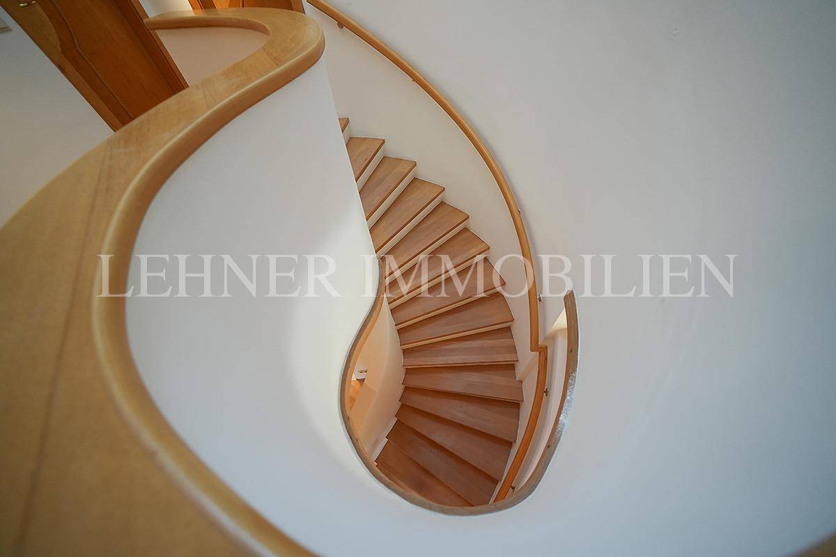 Detailansicht der geschwungenen Holztreppe mit natürlichem Lichteinfall.