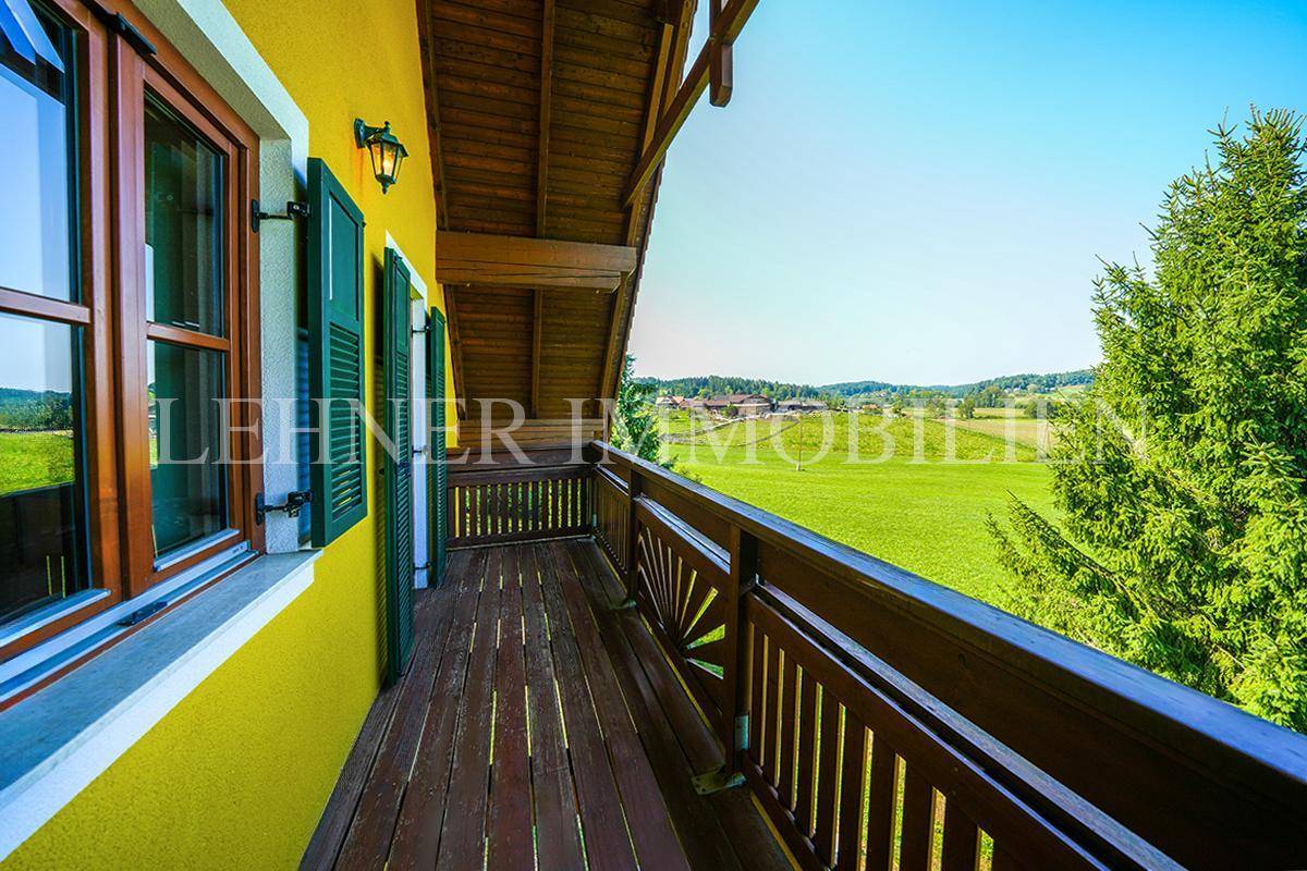 Langer Holzbalkon mit traditionellem Geländer und Panoramablick auf die Natur.