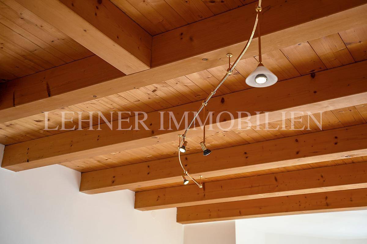 Sichtbare Holzbalkendecke mit integrierten Strahlern und rustikalem Charme.