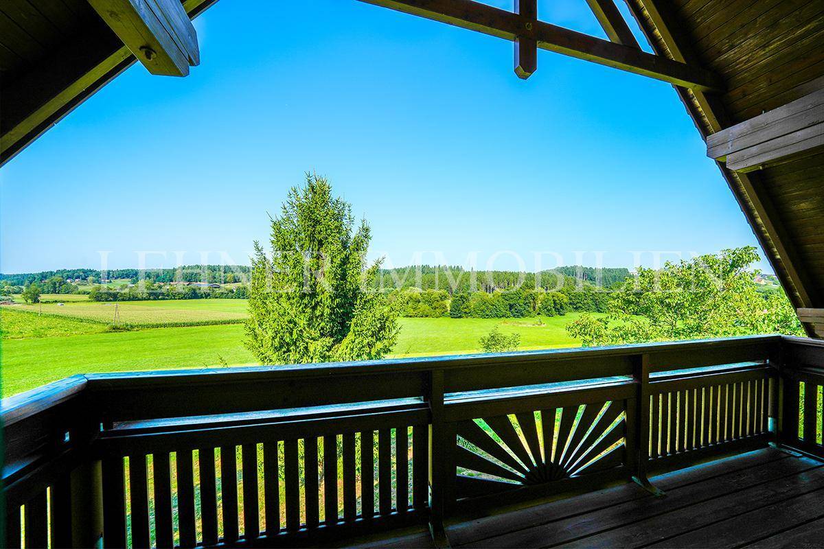 Holzbalkon mit weitem Blick über die grüne Landschaft und die umliegenden Felder.