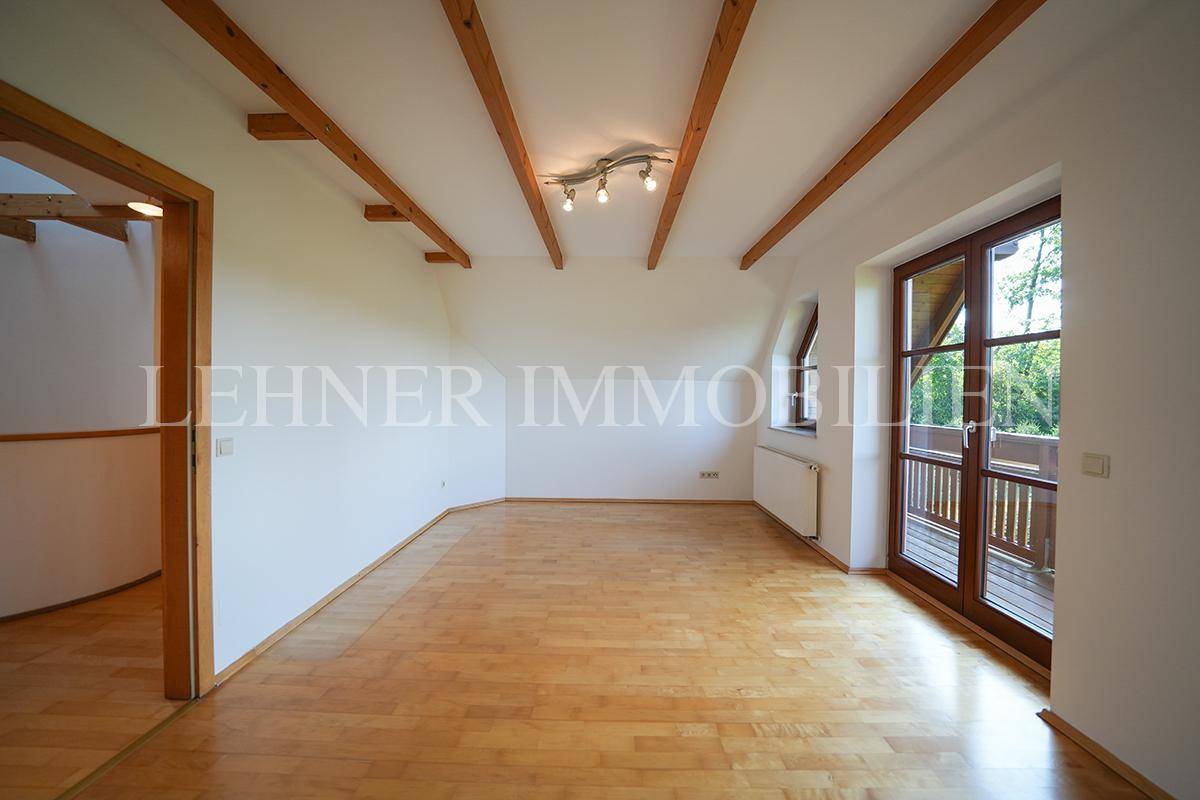 Geräumiges Schlafzimmer im Dachgeschoss mit Holzboden und Zugang zum Balkon.